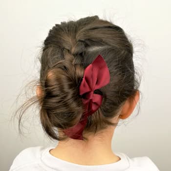 Peinado de moño con trenza superior y acabado con un buen lazo